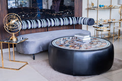 Modern living room with a round black coffee table, gray sofa, and decorative items.