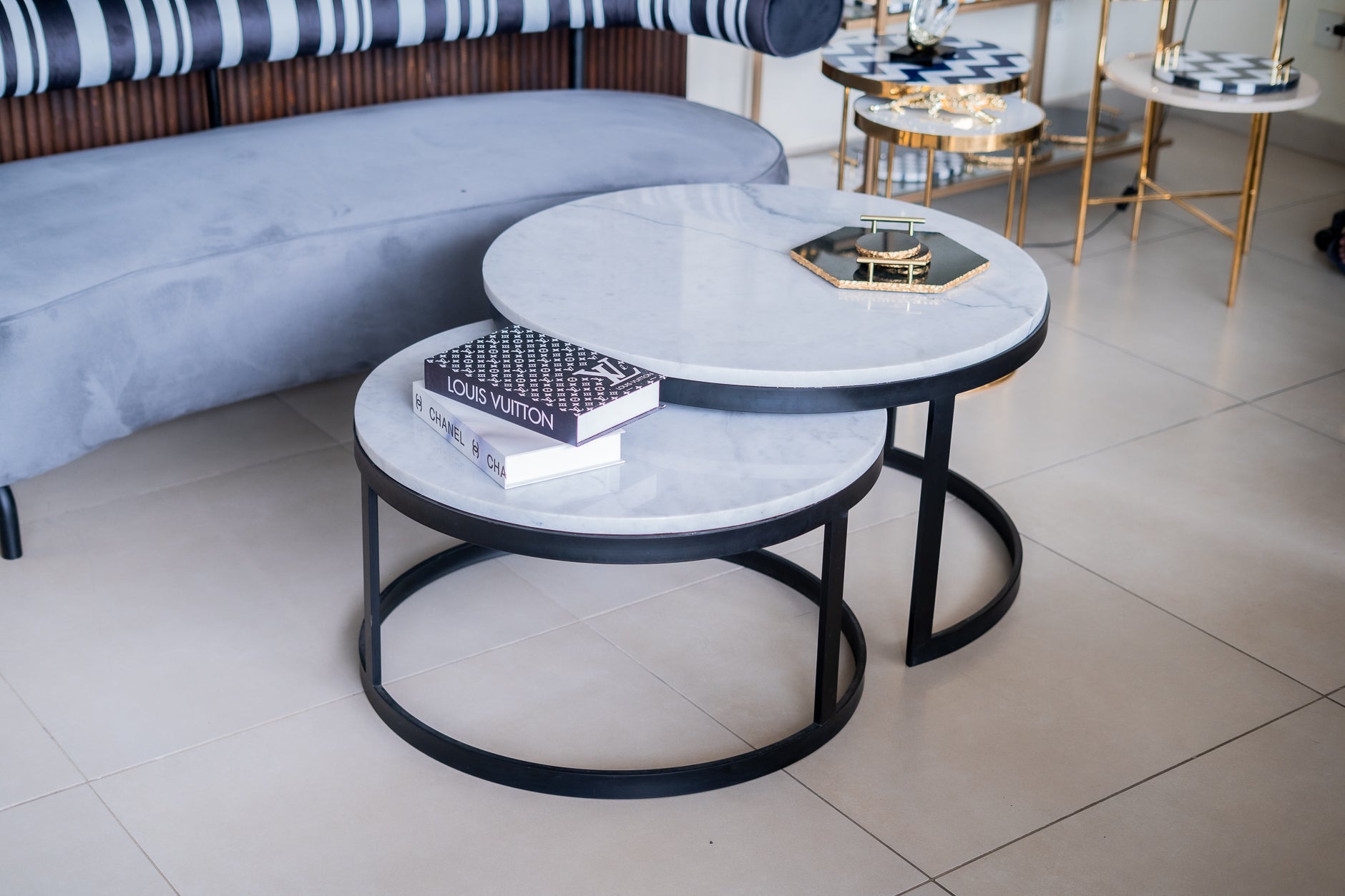 Round marble coffee table with black metal base in a living room setting.