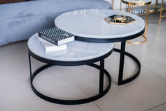 Two round marble coffee tables with black metal frames on a light-colored floor.