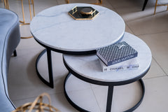 Two marble coffee tables with luxury brand boxes on a tiled floor.