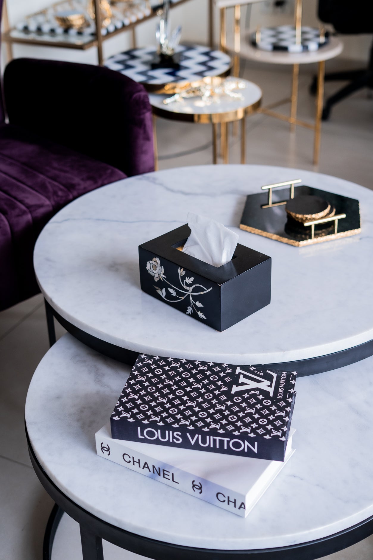 Round marble coffee table with a tissue box, books, and decorative items in a stylish interior setting.