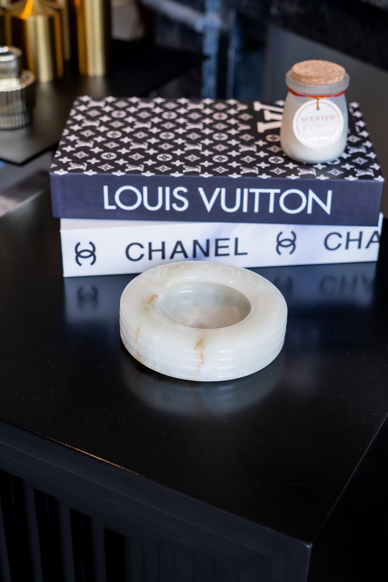 Marble ring on a black surface with a Louis Vuitton box and Chanel candle in the background.