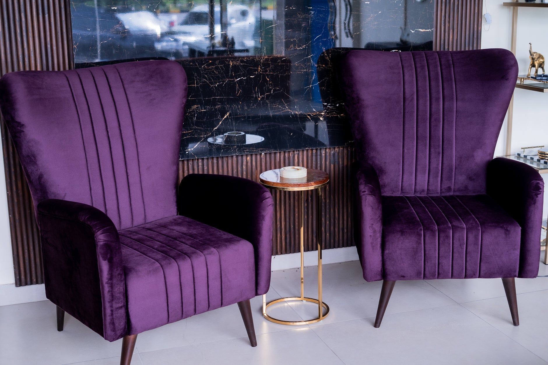 Two purple armchairs with a small round table in a room with a window.