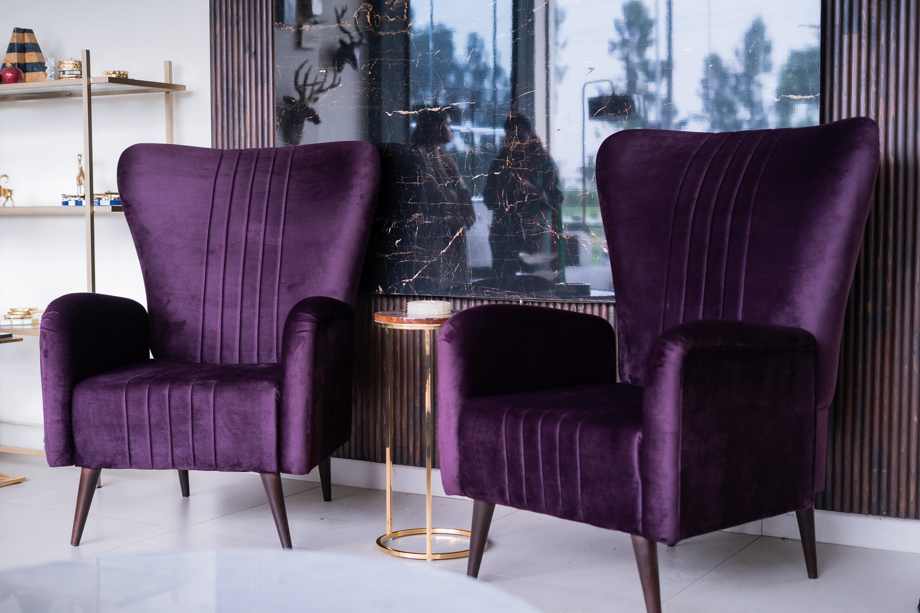 Two purple armchairs in a modern interior setting with a glass table and decorative items.