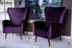 Two purple armchairs in a room with a side table and decorative elements.