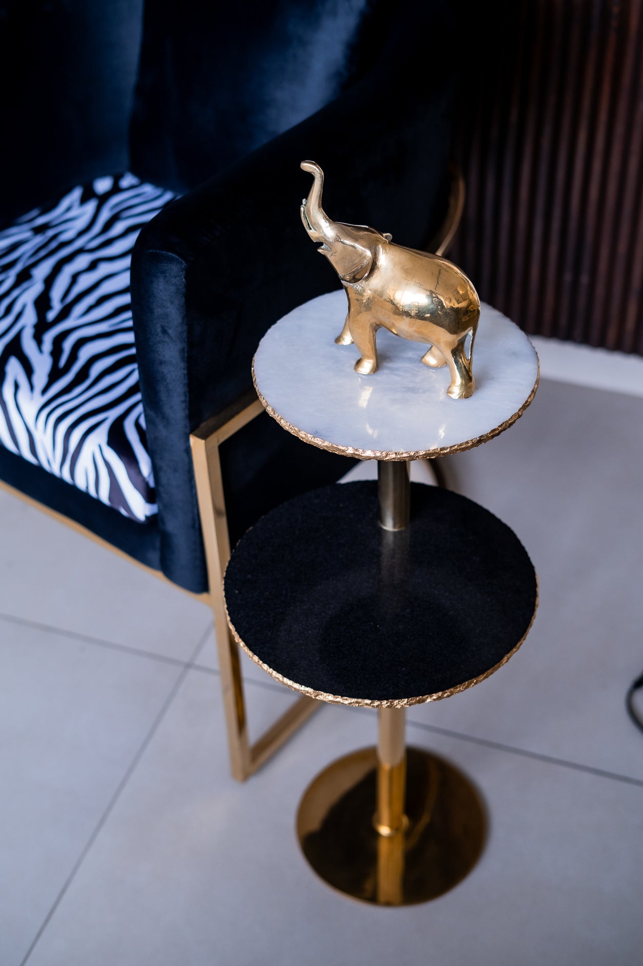 Gold elephant figurine on a marble-top side table with black base.