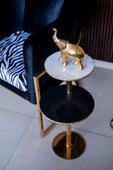 Gold elephant figurine on a marble-top side table with black base.
