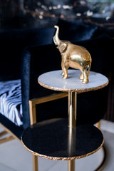 Gold elephant figurine on a three-tiered stand with a blurred background