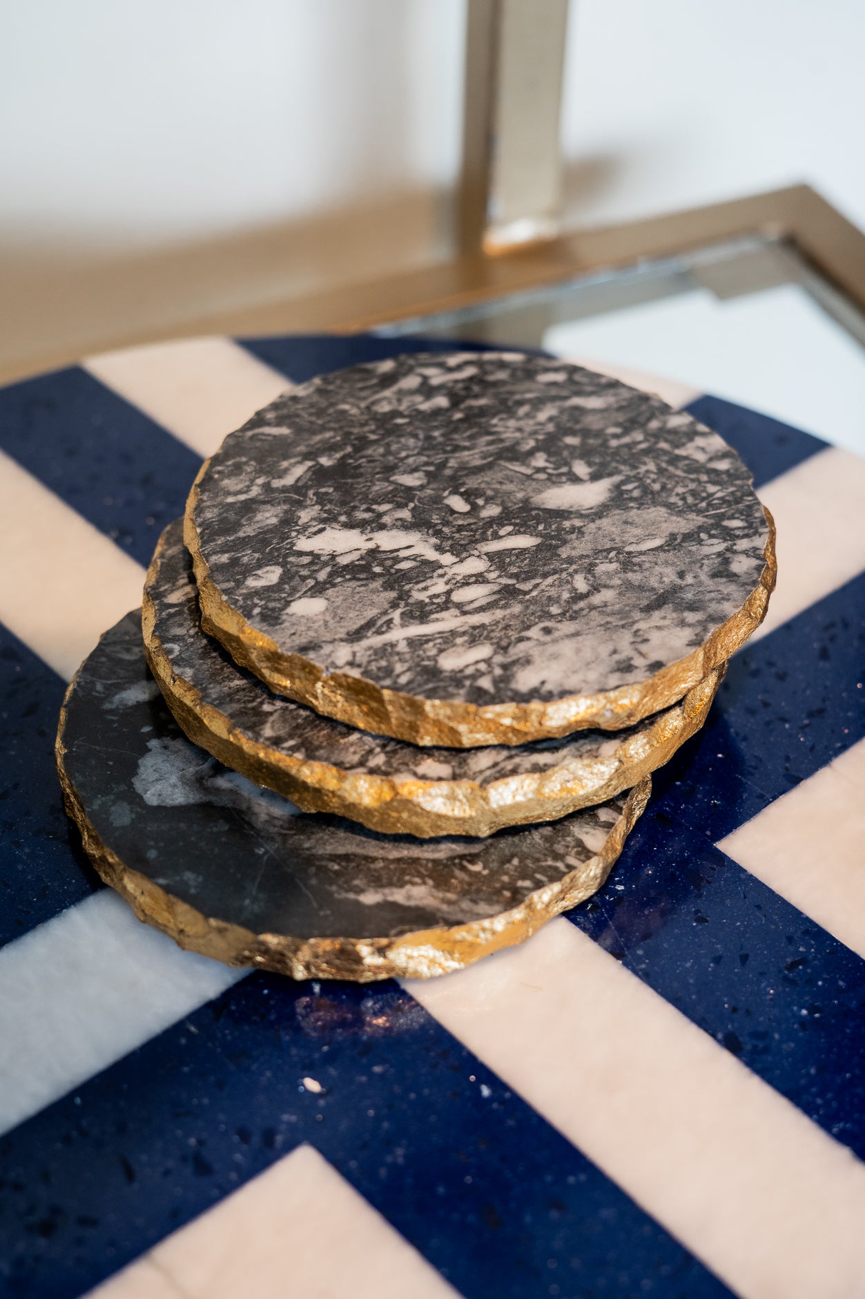 Stack of round, dark stone coasters on a blue and white checkered surface