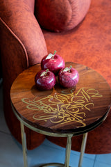 Wooden stool with gold calligraphy and three red apples on a red couch background