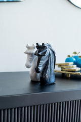 Two horse-shaped figurines on a dark surface with a blurred background