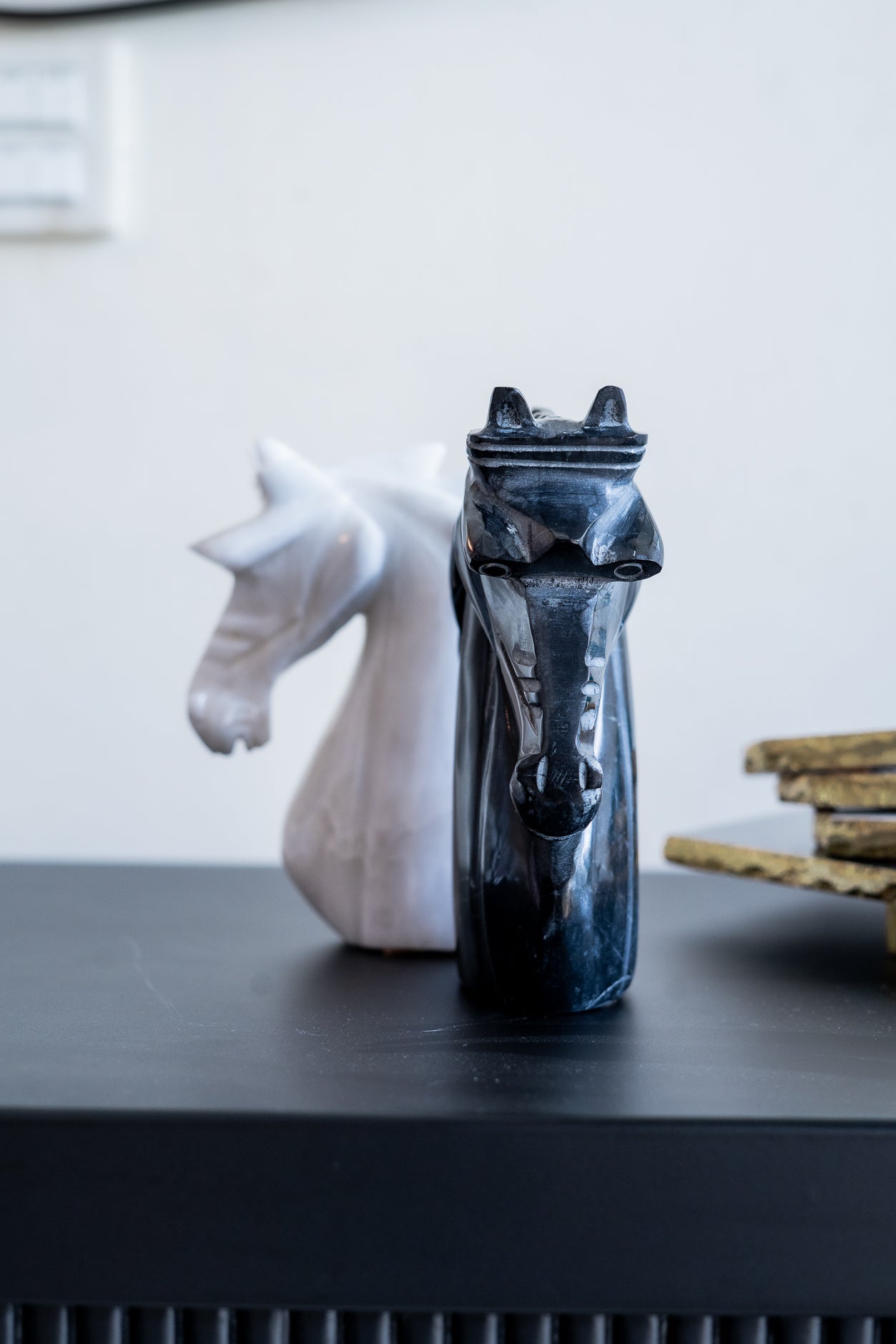 Decorative horse head sculptures on a dark surface with a blurred background