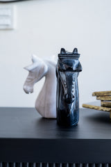 Decorative horse head sculptures on a dark surface with a blurred background