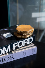 Book titled 'Dior' with a piece of cake on top, against a blurred background