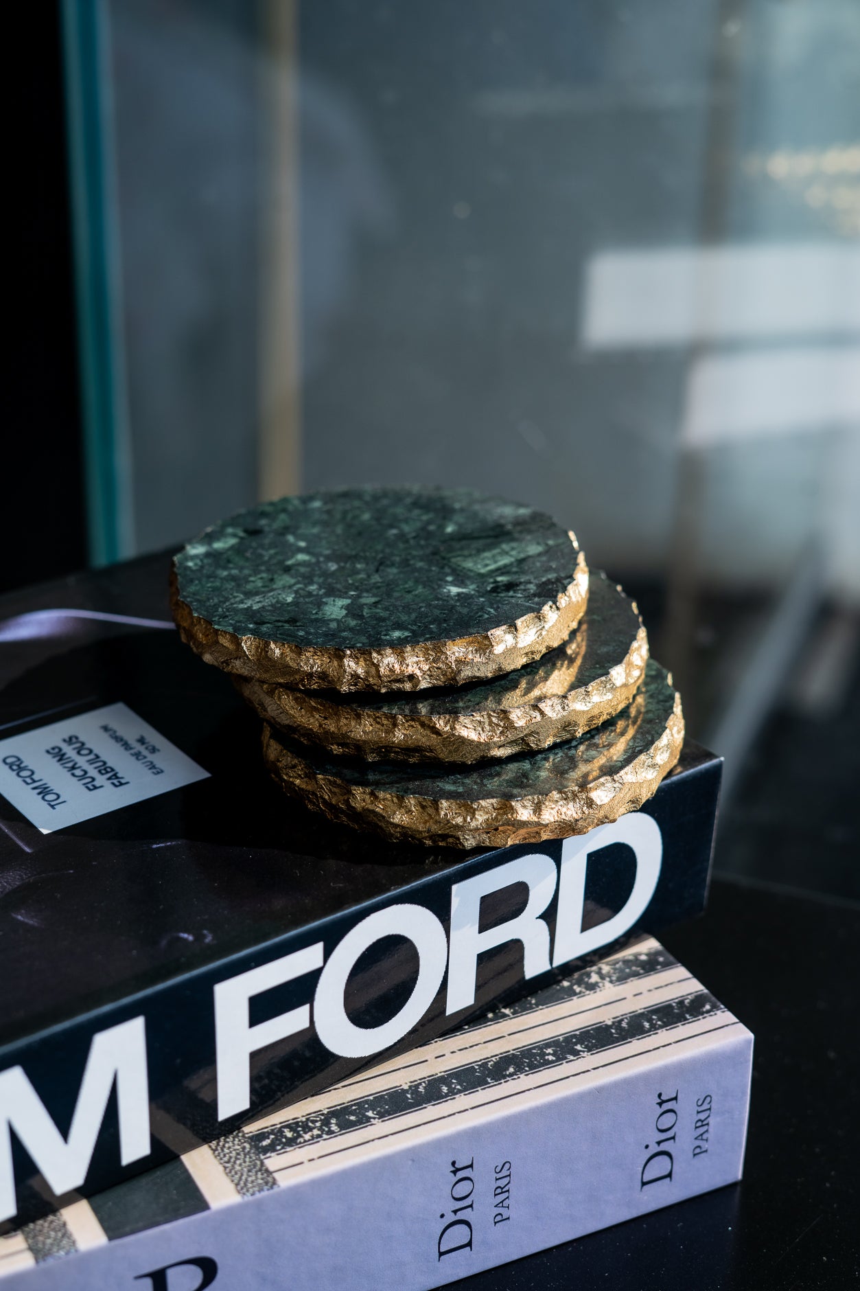 Stack of green marble coasters on a book titled 'Tom Ford' with a blurred background