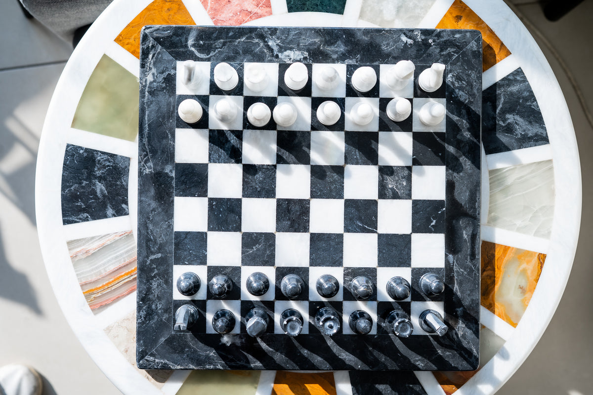 Marble-patterned chessboard with chess pieces on a decorative table.