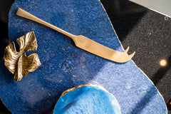 Gold leaf-shaped object and knife on a blue textured surface