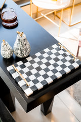 Decorative black and white checkered tray on a table with decorative items.