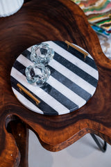 Round black and white striped tray with gold accents on a wooden surface