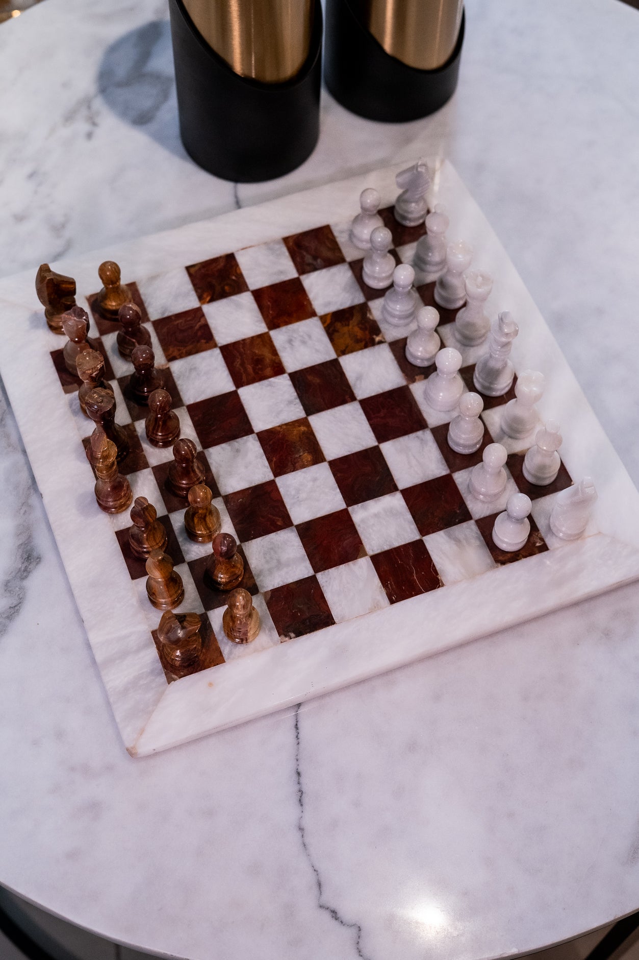 Marble chessboard with wooden and glass chess pieces on a marble surface.