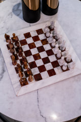 Marble chessboard with wooden and glass chess pieces on a marble surface.