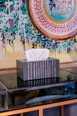 Tissue box on a reflective surface with a colorful abstract painting in the background