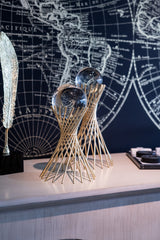 Decorative object with glass spheres on a surface in front of a world map.