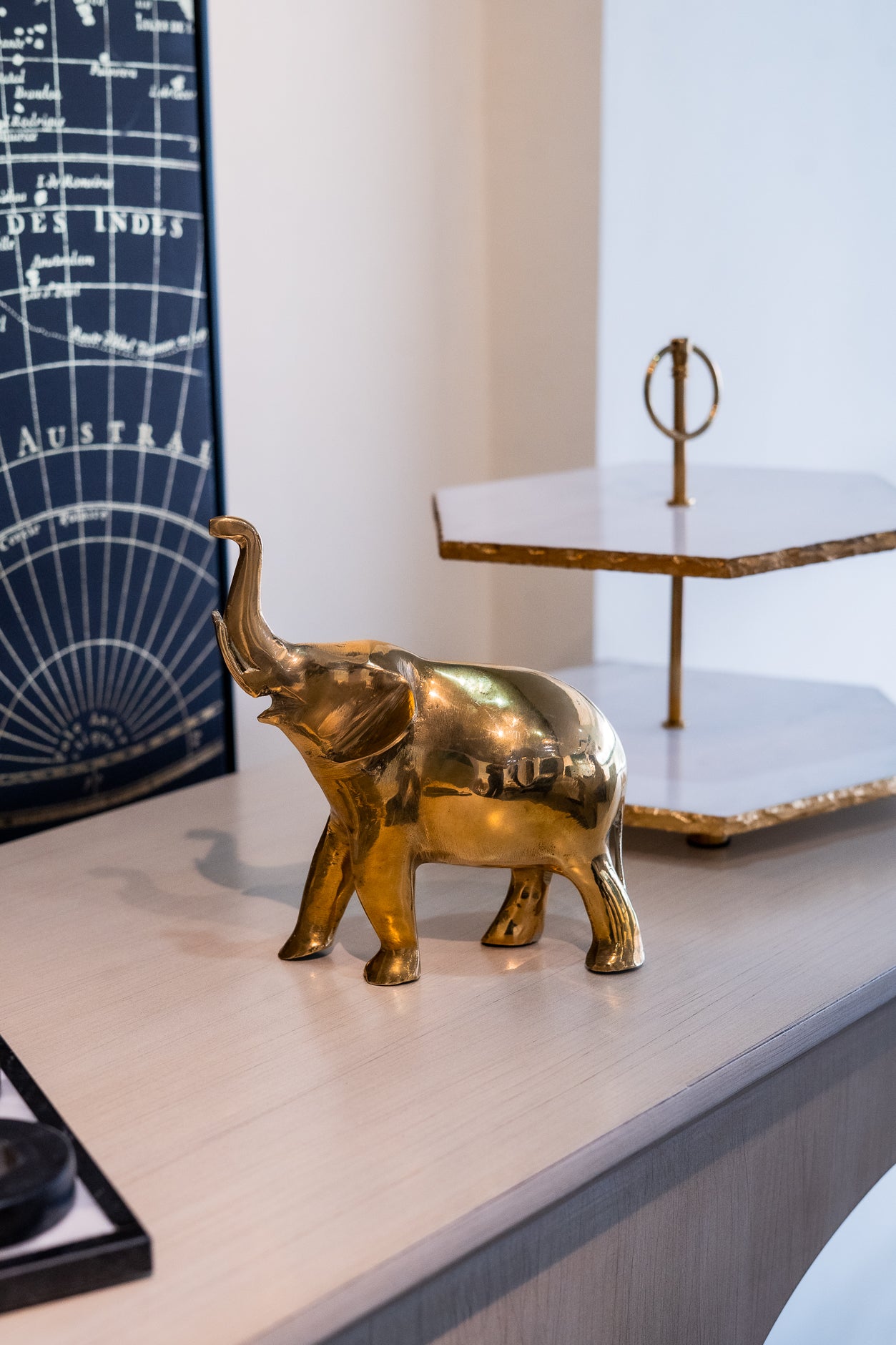 Gold elephant figurine on a surface with a map and decorative object in the background