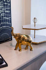 Gold elephant figurine on a surface with a map and decorative object in the background