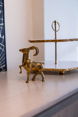 Brass ram sculpture on a shelf with a blurred background