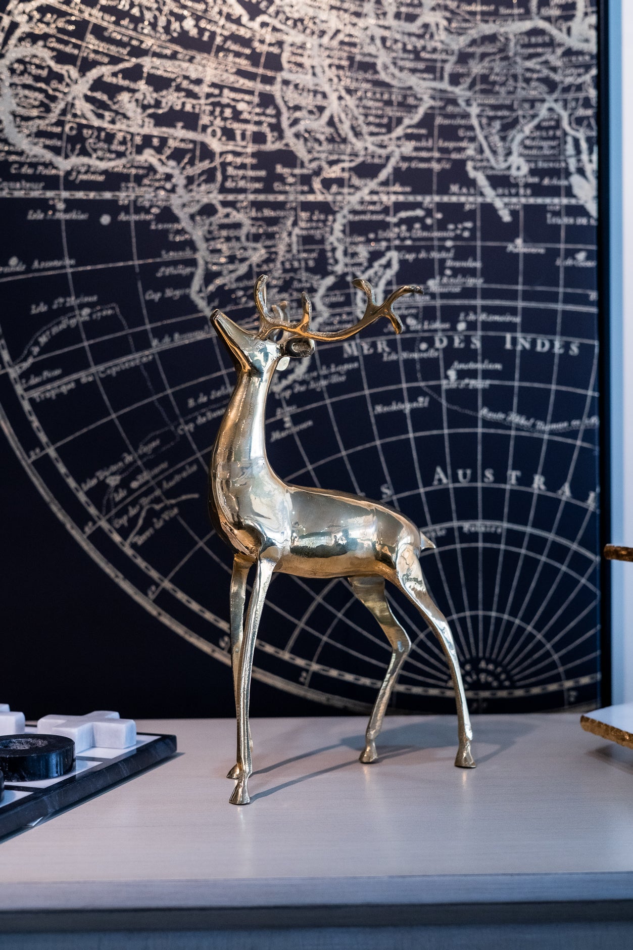 Gold deer figurine on a surface with a world map in the background