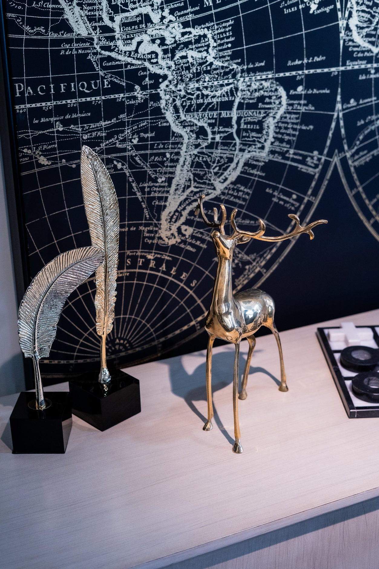 Decorative metal deer figurine on a stand with a world map in the background