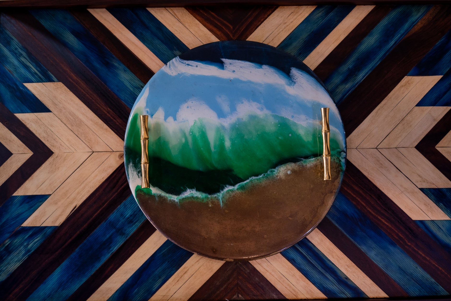 Decorative round object with green and blue design on a wooden floor with geometric pattern