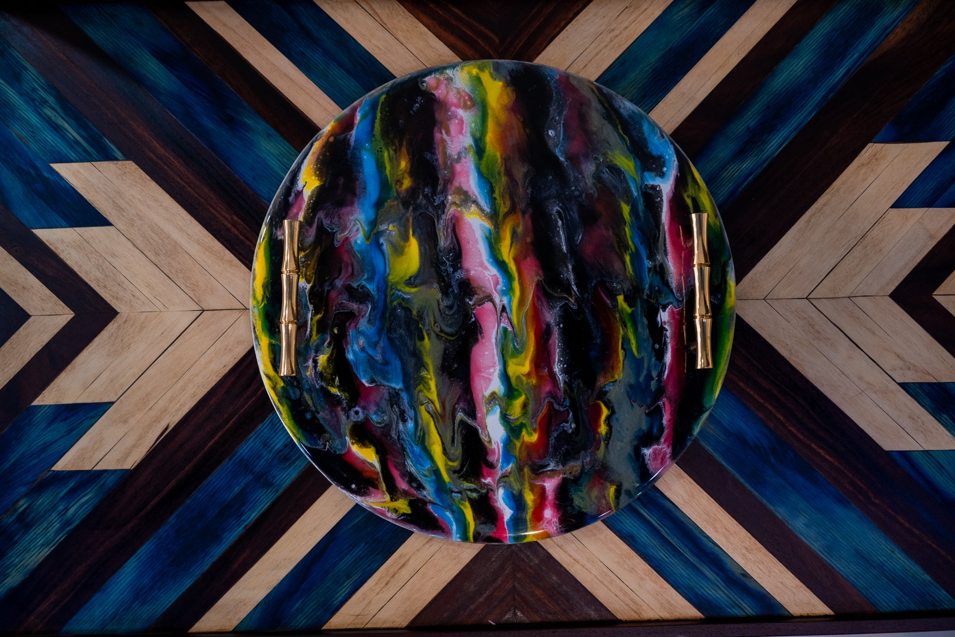 Colorful abstract painting on a round surface with a geometric patterned floor.