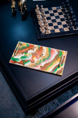 Colorful abstract painting on a dark surface with a chessboard in the background