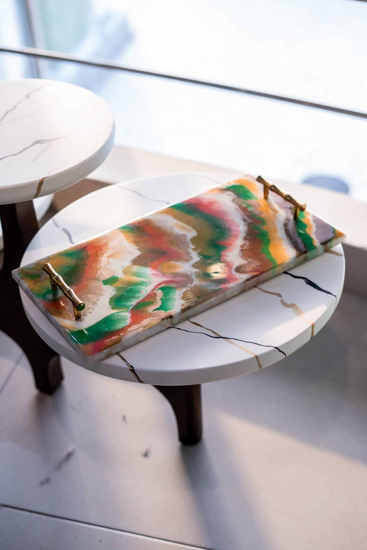 Colorful rectangular tray with gold handles on a round marble table