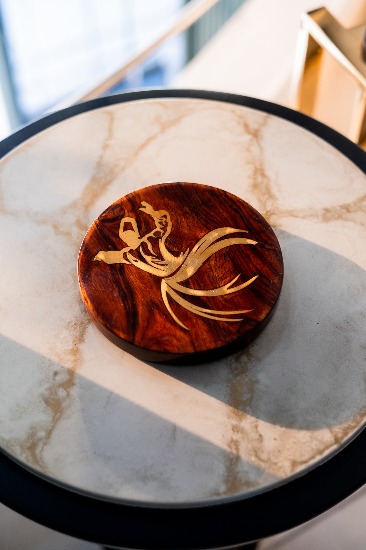 Wooden coaster with a gold design on a marble surface