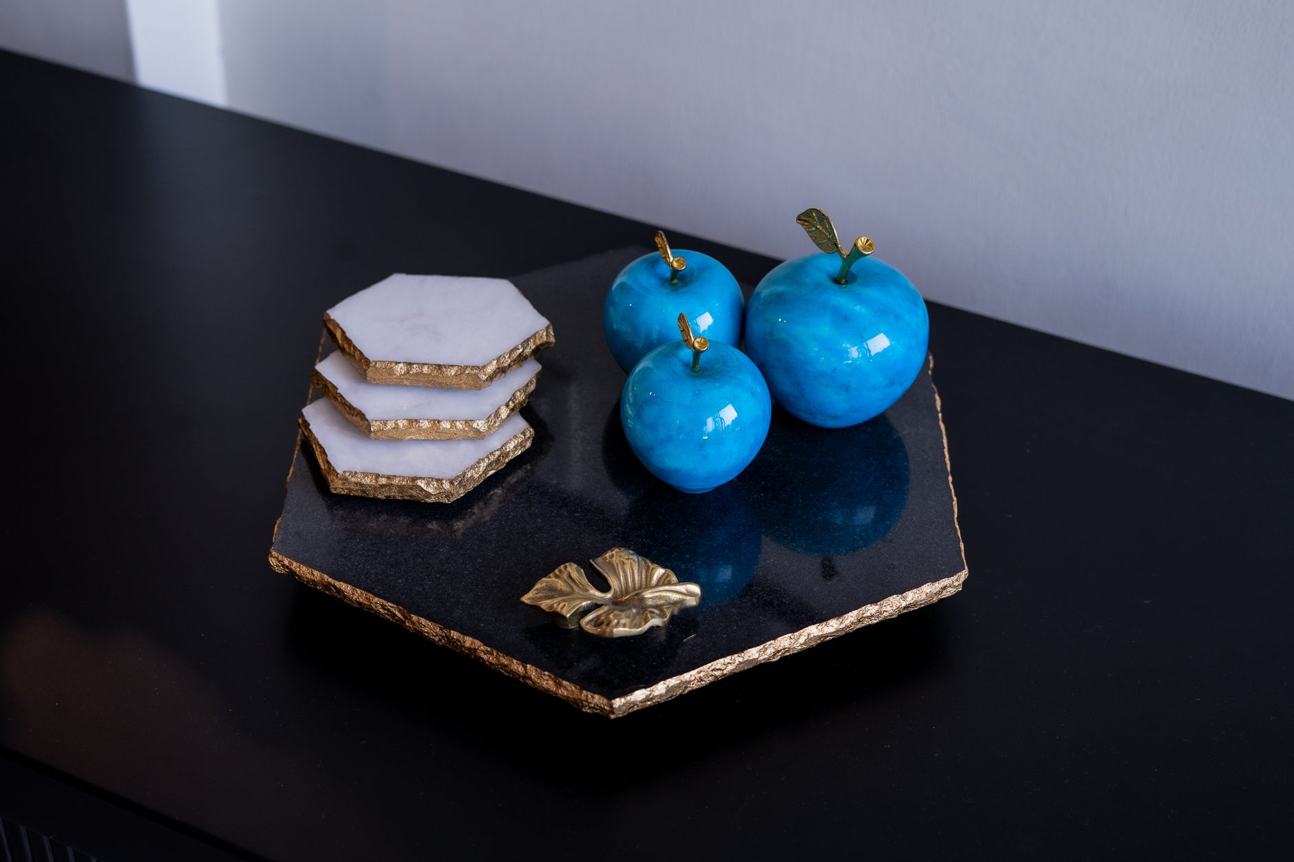 Blue decorative fruits on a black and gold hexagonal plate with a white background