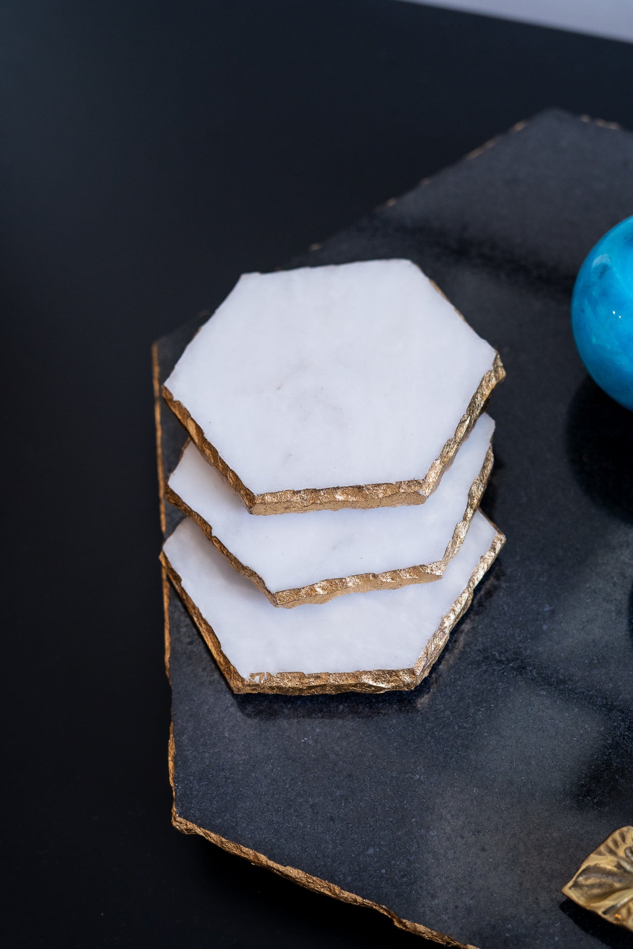Hexagonal cookies stacked on a dark surface with a blue object in the background