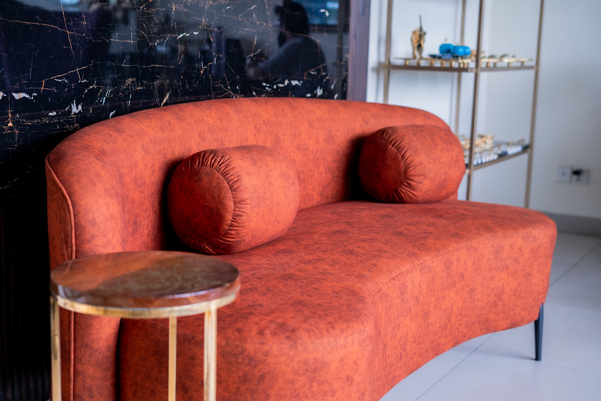 Orange sofa with a wooden side table in a room with a black marble wall.