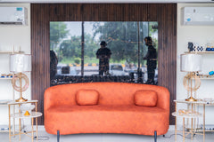 Orange sofa in a modern living room with a large mirror reflecting people and outdoor scenery.